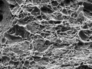 High magnification SEM image reveals a dimpled morphology (micro-void coalescence) at the location of ductile overload, resulting from opening the secondary crack. 