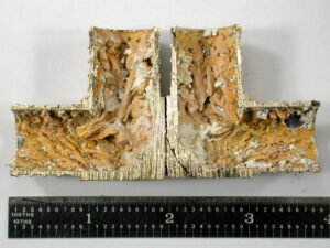 A cross-section cut through one of the fittings revealed heavy orange and white internal deposits. The deposit morphology indicated low flow velocity or a stagnant condition over an extended period of time.