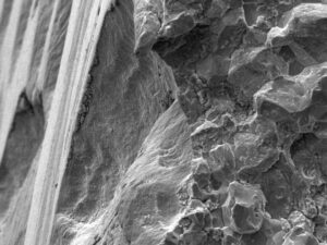 A high magnification SEM view of the fracture origin indicates the fracture initiated at the bottom of a dot peen indentation on the shaft OD surface. 