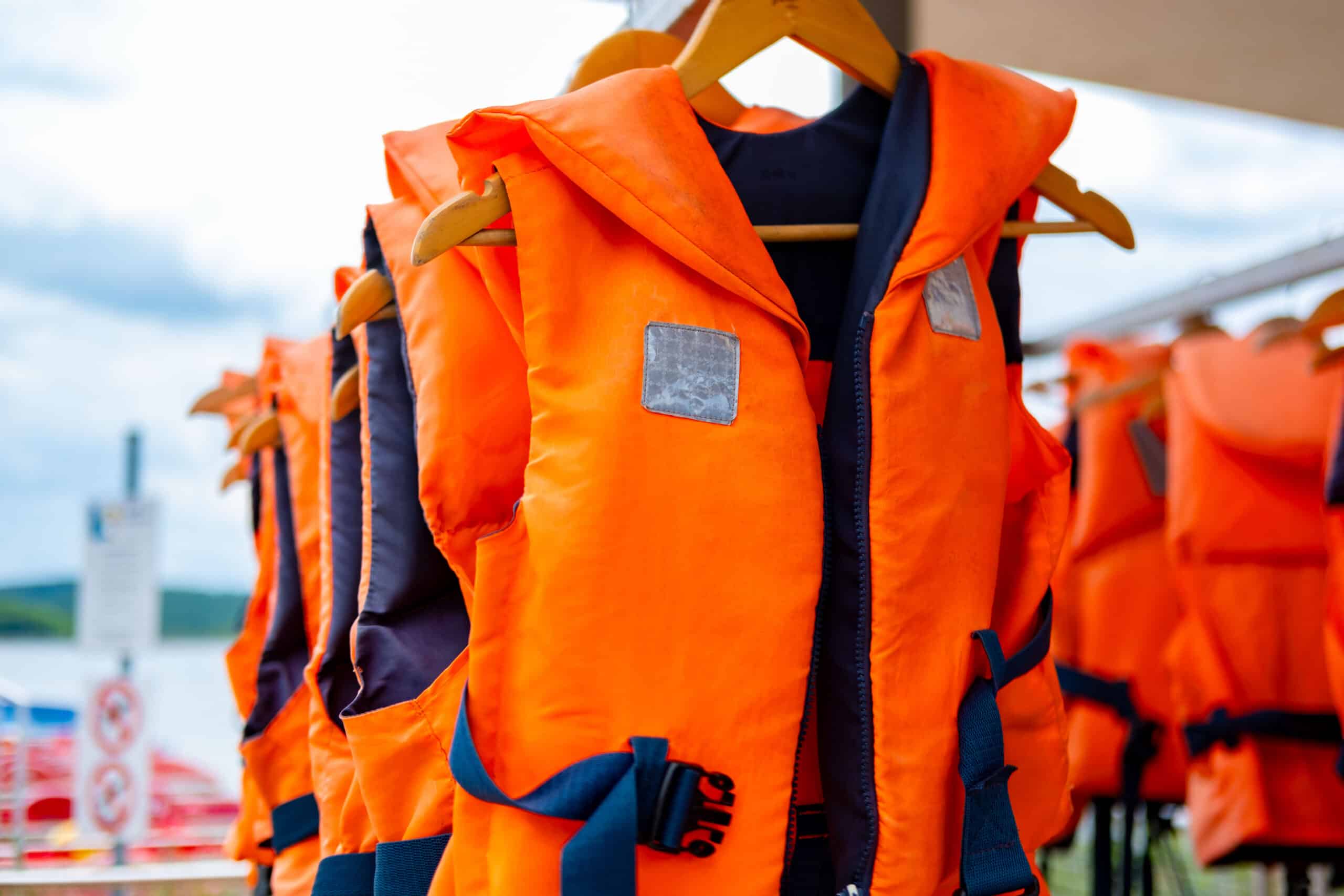 Bright orange life vests hanging, Safety equipment water sports, Summer activity preparation, water safety, adventure, and summer recreation, life vests available for aquatic fun, Outdoor leisure gear