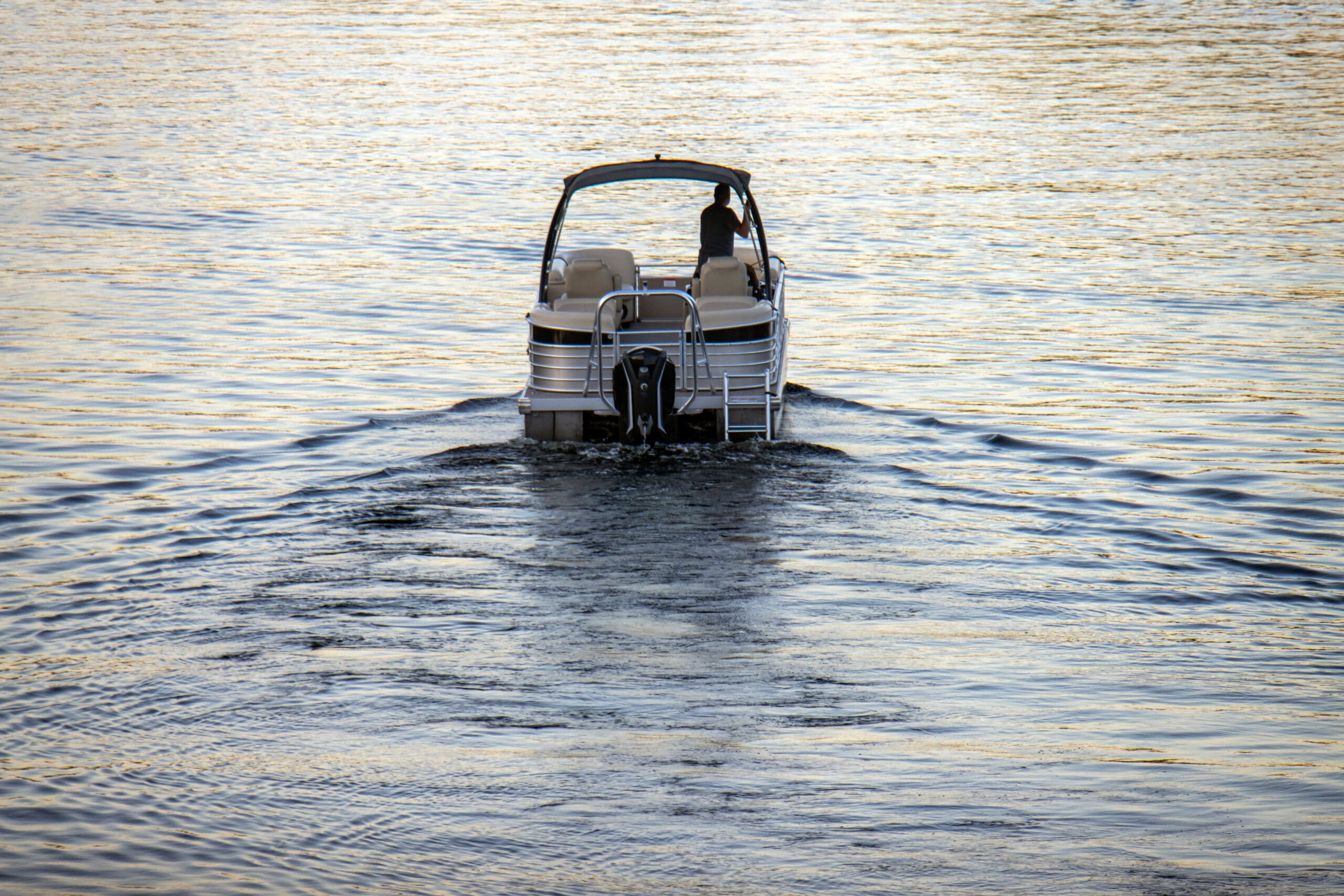 pontoon boat with canopy heading out of the harbor