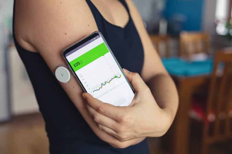 Woman checking glucose level with a modern technology remote sensor and mobile phone, without blood. Diabetes treatment. Contextual Inquiry