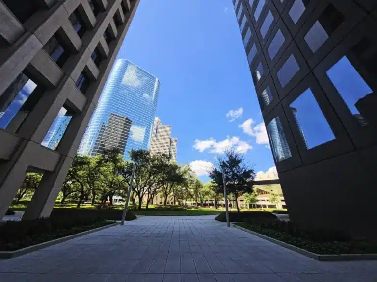 This photo shows modern office skyscrapers framing the Houston skyline from a pedestrian plaza in downtown Houston, Texas.