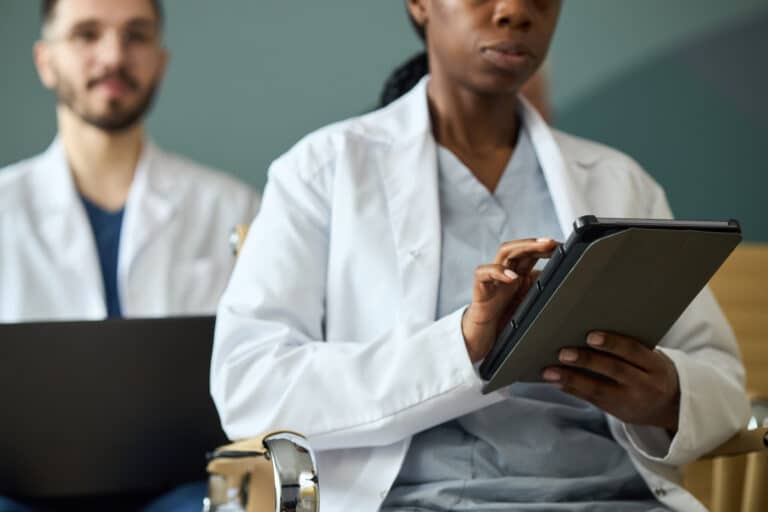 Healthcare professionals focused on data documentation during medical procedures using digital tablets, emphasizing collaborative teamwork in a clinical setting. Institutional Review Board - IRB