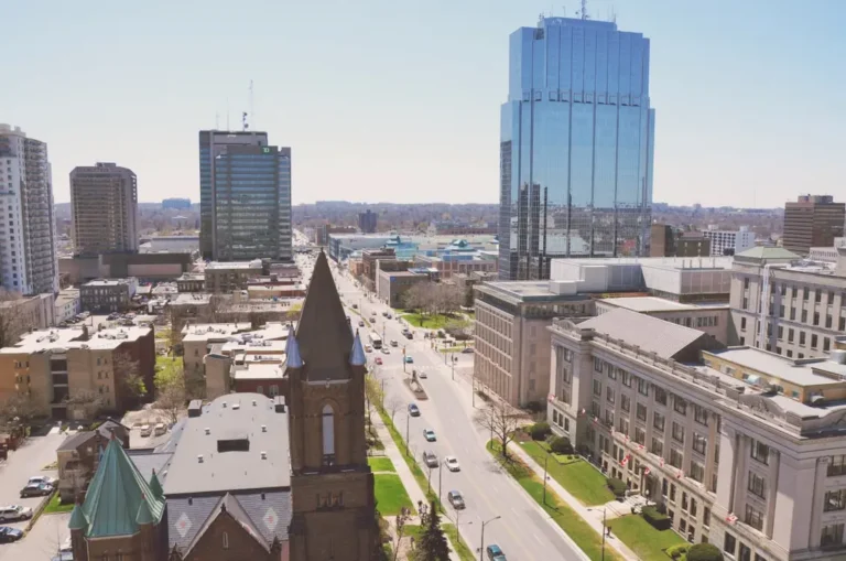 London, Ontario, Canada, looking down a main street with prominent local landmarks like the historic church steeple in the foreground and the prominent glass high-rise towers in the background.