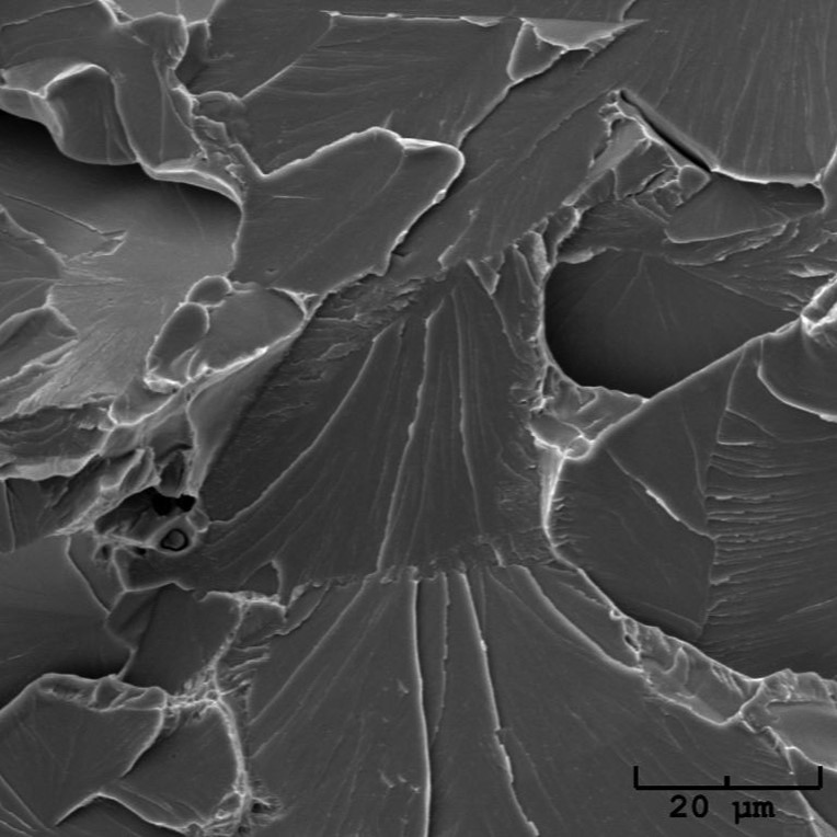 High magnification scanning electron microscope SEM image of a brittle transgranular cleavage fracture surface