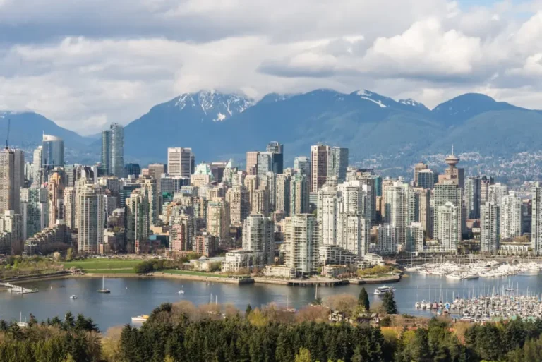 Vancouver, British Columbia, Canada, featuring False Creek/Yaletown, the dense high-rise architecture, and the North Shore Mountains in the background.